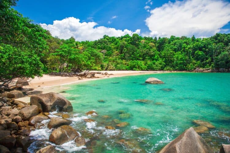Plage sauvage de Khao Lak avec sable clair, rochers et eau turquoise.