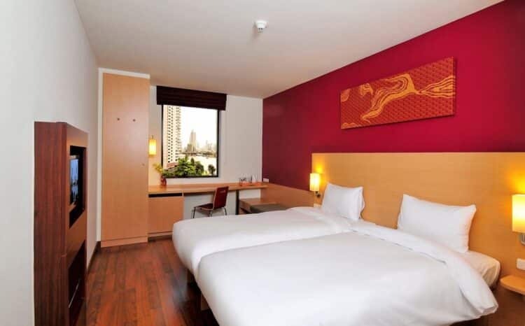 Chambre moderne et lumineuse avec lits jumeaux dans un hôtel à Bangkok.