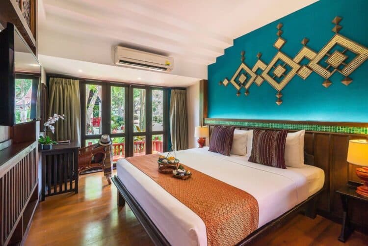 Chambre élégante à la décoration thaïlandaise avec lit double et ouverture sur le jardin.