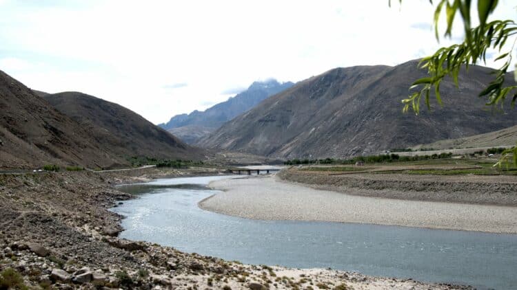 Vallée du Brahmapoutre traversant un paysage montagneux avec un pont et des rives arides en Assam.