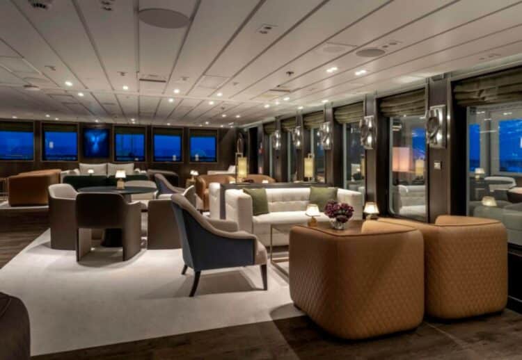 Grand salon lounge d’un navire d’expédition en Antarctique avec assises confortables et vue mer.