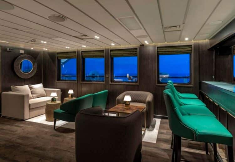 Salon panoramique d’un navire d’expédition en Antarctique avec grandes fenêtres vue mer.