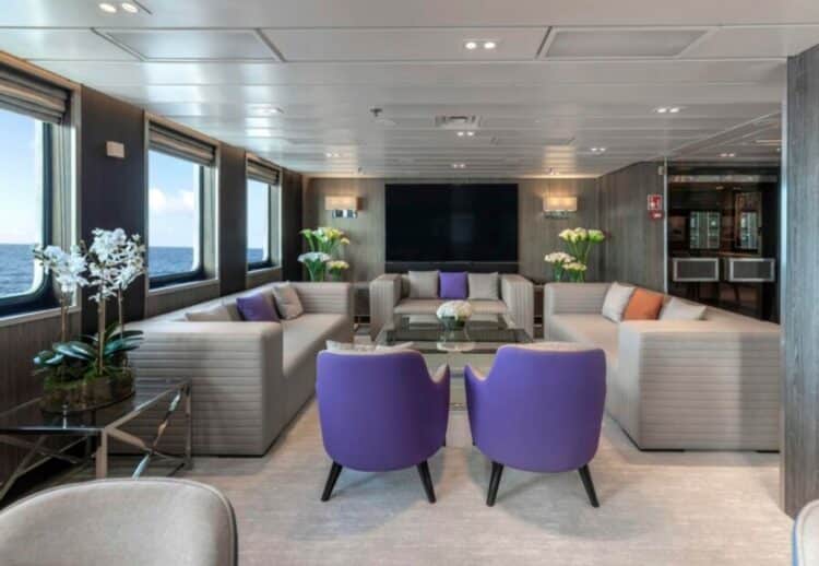 Salon intérieur d’un navire d’expédition en Antarctique avec canapés et grandes fenêtres sur l’océan.