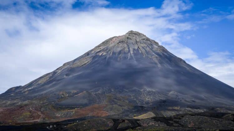 Volcan Pico do Fogo au Cap-Vert dominant un paysage volcanique sombre sous un ciel bleu