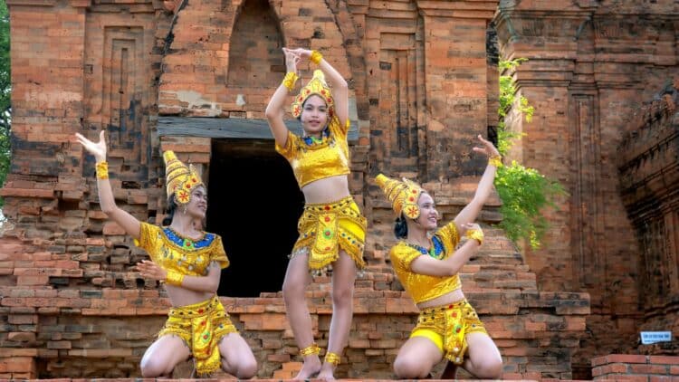 Danseuses en costumes traditionnels thaïlandais devant un temple ancien en briques