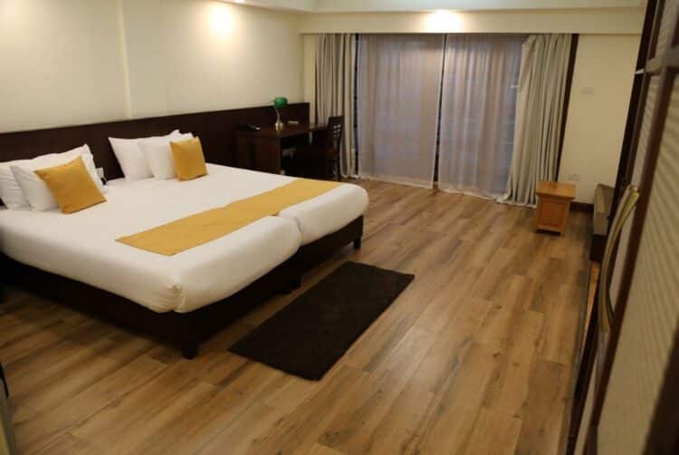 Chambre du Khuru Resort au Bhoutan avec lits jumeaux, murs en bois et ambiance chaleureuse