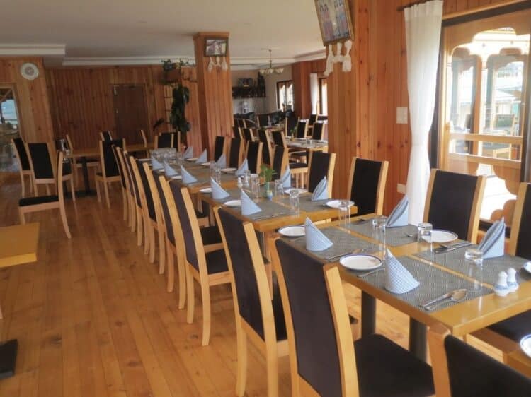 Restaurant du Mandala Hotel avec tables en bois, larges baies vitrées et vue sur les montagnes