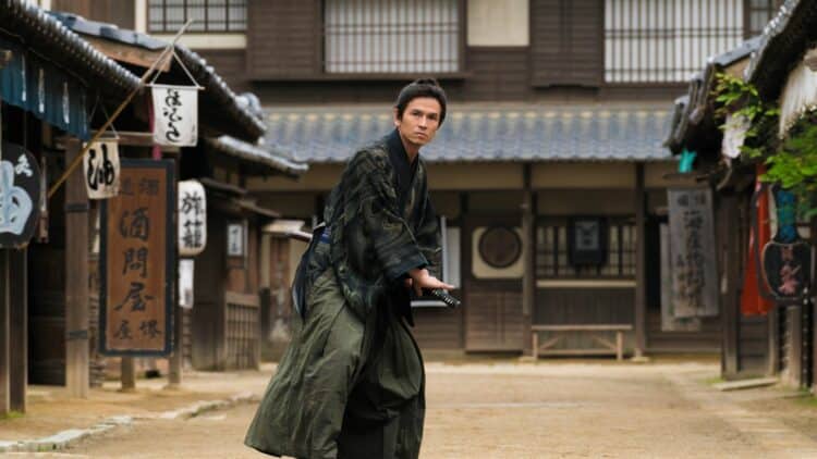 Homme en tenue de samouraï avec katana dans une rue traditionnelle japonaise
