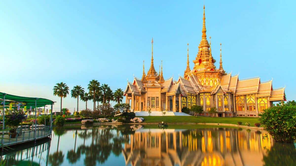 Temple bouddhiste doré en Thaïlande avec architecture traditionnelle et reflet dans un bassin
