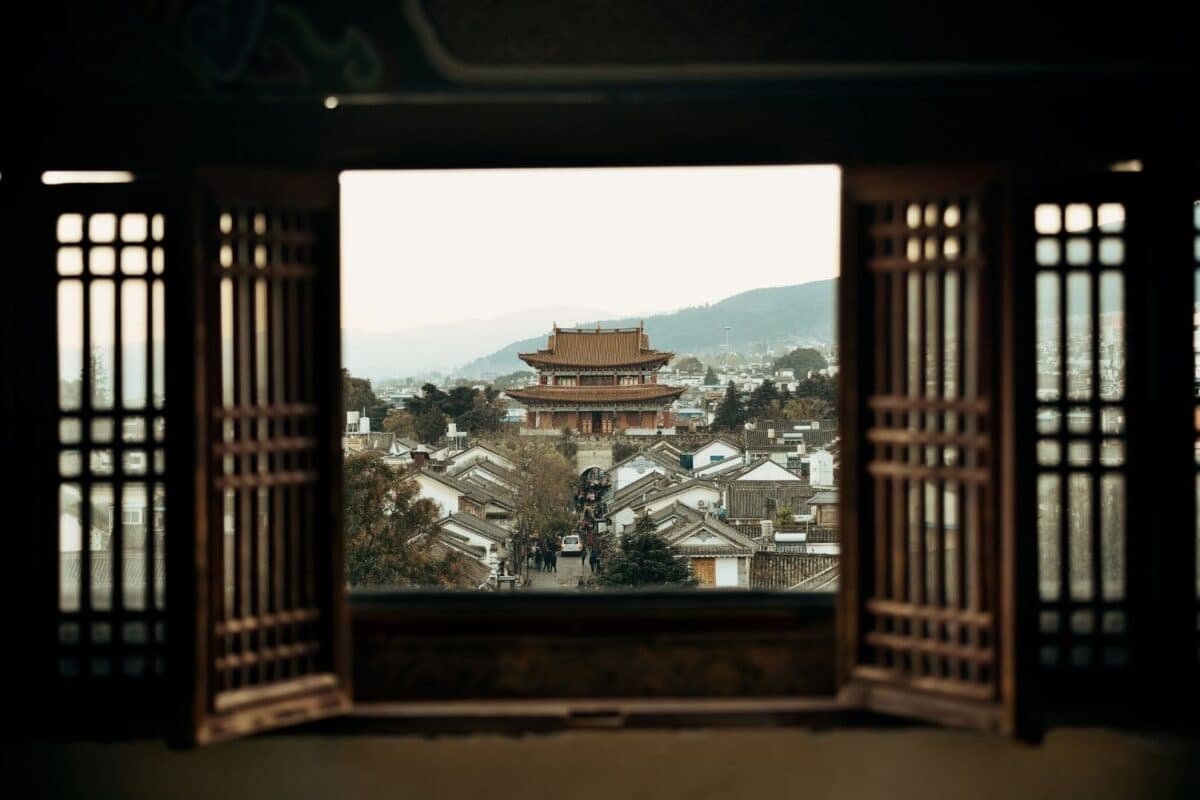Vue sur une ville traditionnelle du Yunnan depuis une fenêtre en bois