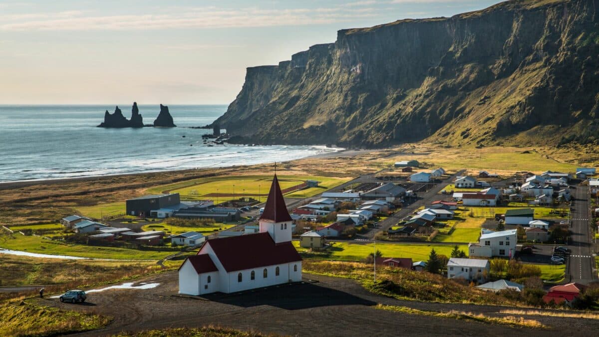 eglise blanche de vik surplombant village et falaises sur la cote sud islandaise