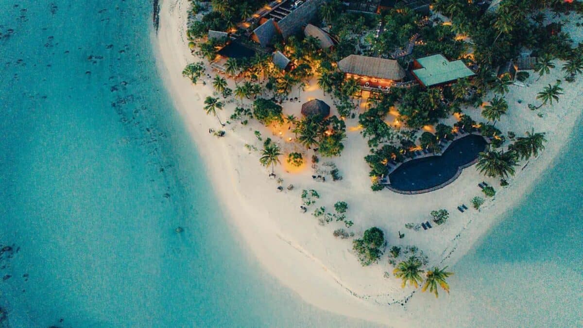 vue aérienne d’une île privée avec plage de sable blanc et resort dans un lagon turquoise
