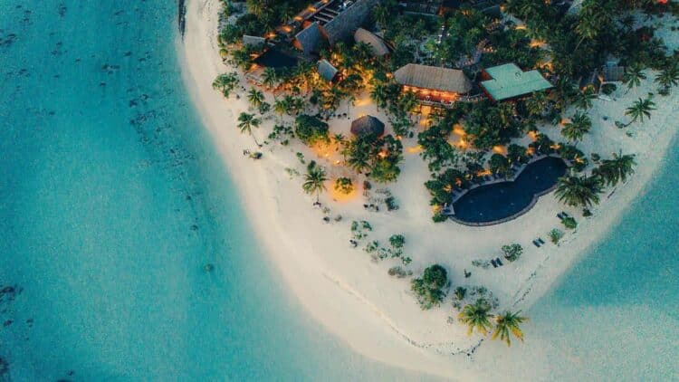 vue aérienne d’une île privée avec plage de sable blanc et resort dans un lagon turquoise