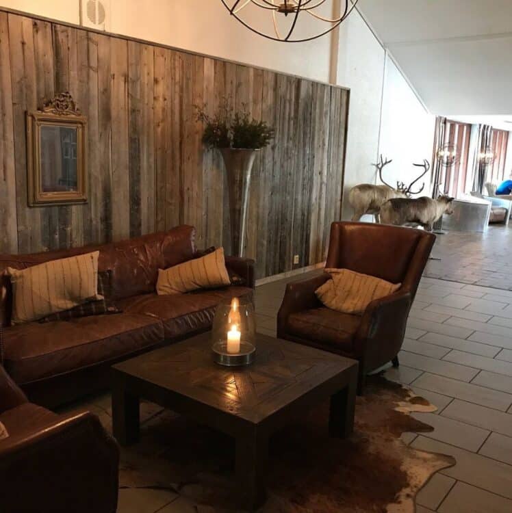 Salon d’hôtel en bois avec canapé en cuir et décoration rustique en Laponie