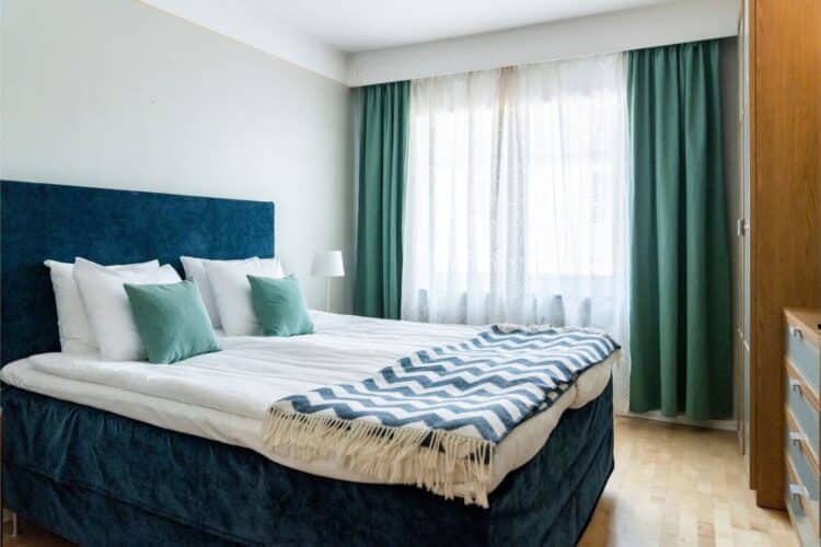 Chambre d’hôtel lumineuse avec lit double et rideaux verts en Suède
