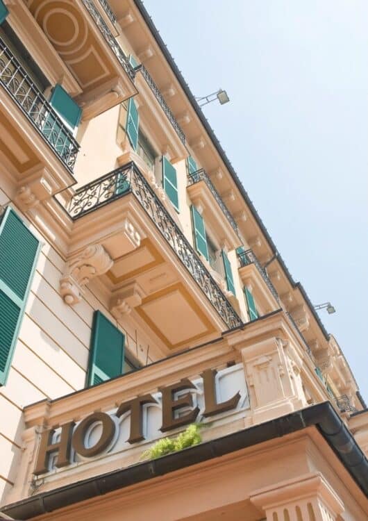 Façade d’hôtel italien avec balcons en fer forgé et volets verts