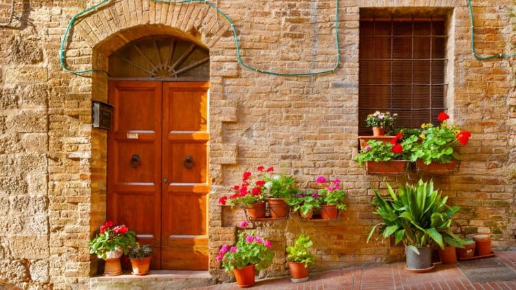 Maison en pierre en Toscane avec porte en bois et pots de fleurs colorés