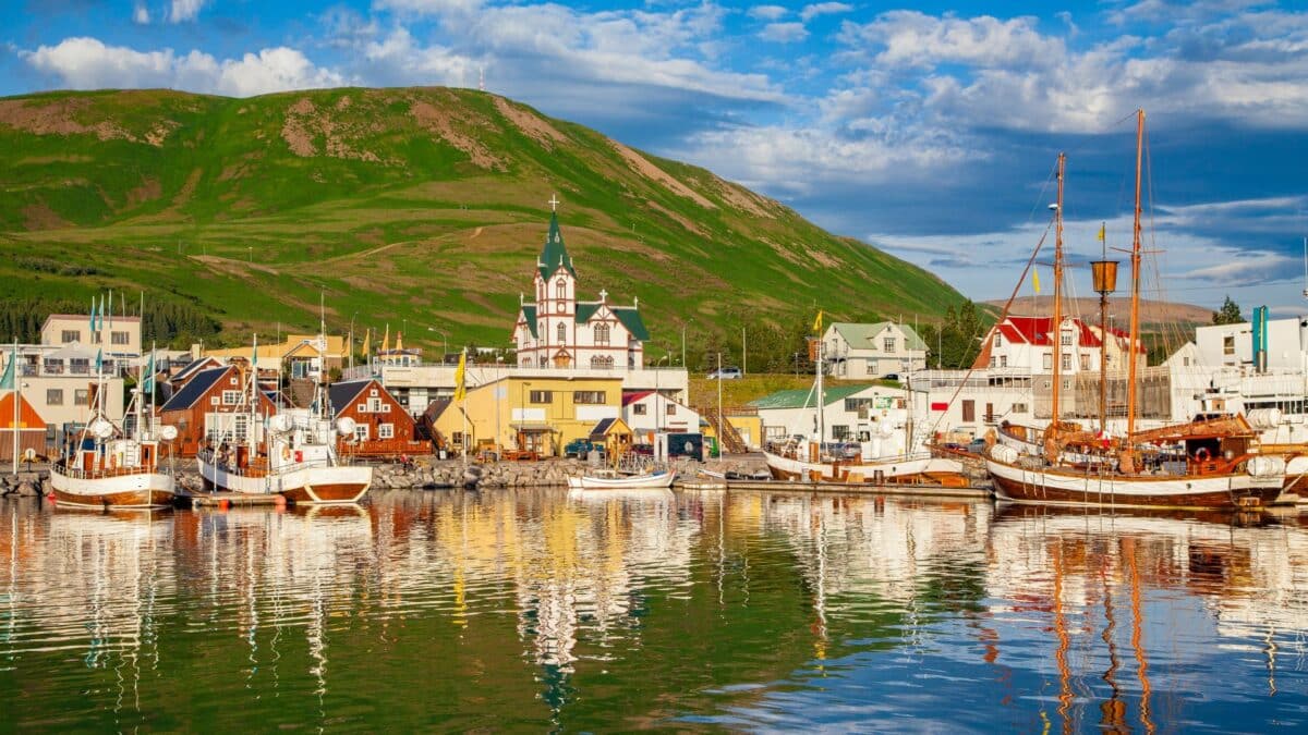 port islandais avec bateaux et maisons colorees refletees dans leau calme