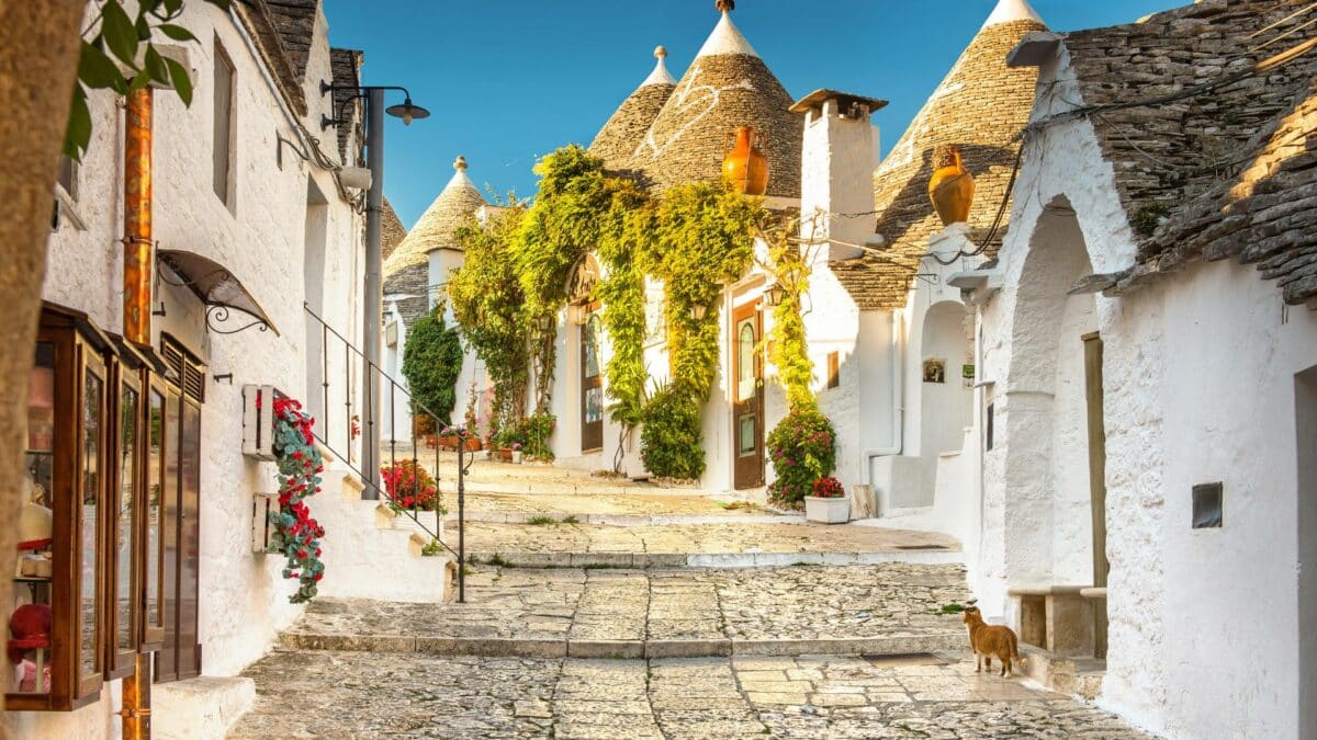Ruelle pavée bordée de maisons trulli blanches avec toits coniques en Italie