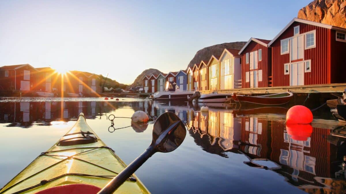 Petit port suédois avec cabanes colorées et kayak au coucher du soleil