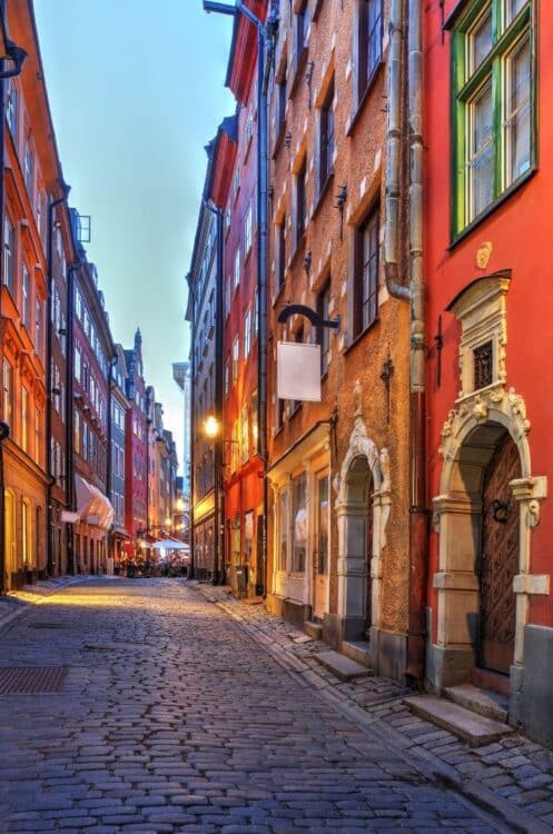 Ruelle pavée de Gamla Stan à Stockholm avec façades colorées et éclairage chaleureux