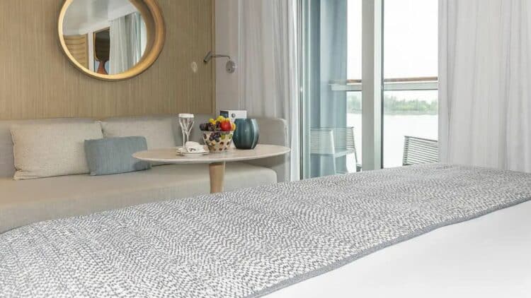 espace repas dans une cabine de croisière avec table, fruits et accès balcon