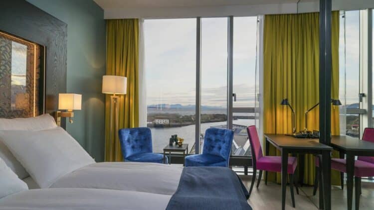 Chambre d’hôtel en Norvège avec grandes baies vitrées, fauteuils et vue sur la mer