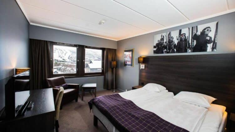 Chambre d’hôtel cosy en Norvège avec vue sur un paysage de montagne enneigé