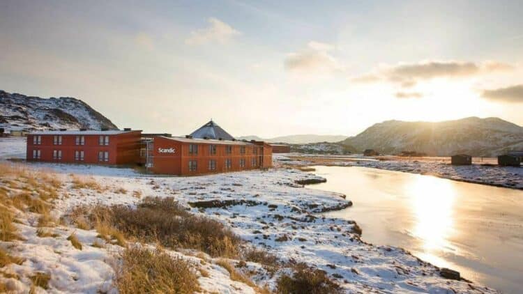 Hôtel Scandic en Norvège situé au bord d’une rivière dans un paysage enneigé au coucher du soleil
