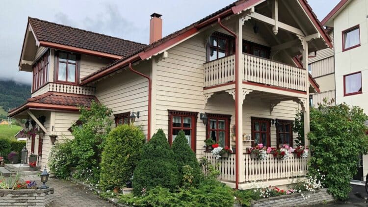 Maison traditionnelle norvégienne en bois avec balcon et jardin fleuri
