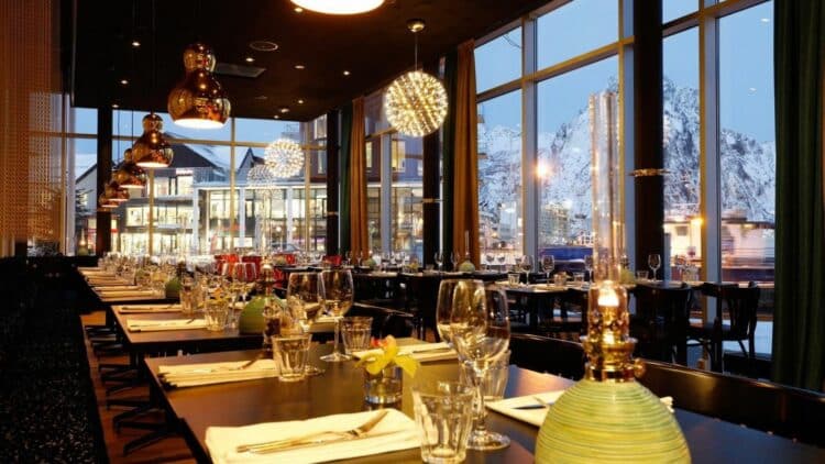 Restaurant avec grandes baies vitrées offrant une vue sur les montagnes enneigées en Norvège