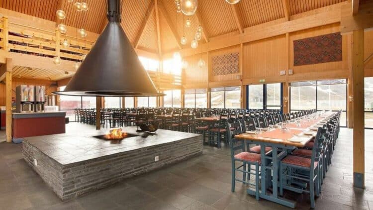 Grande salle de restaurant de style chalet en Norvège avec cheminée centrale et longues tables
