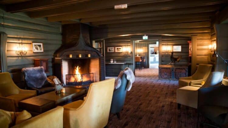 Salon de chalet en Norvège avec cheminée allumée, fauteuils et ambiance chaleureuse