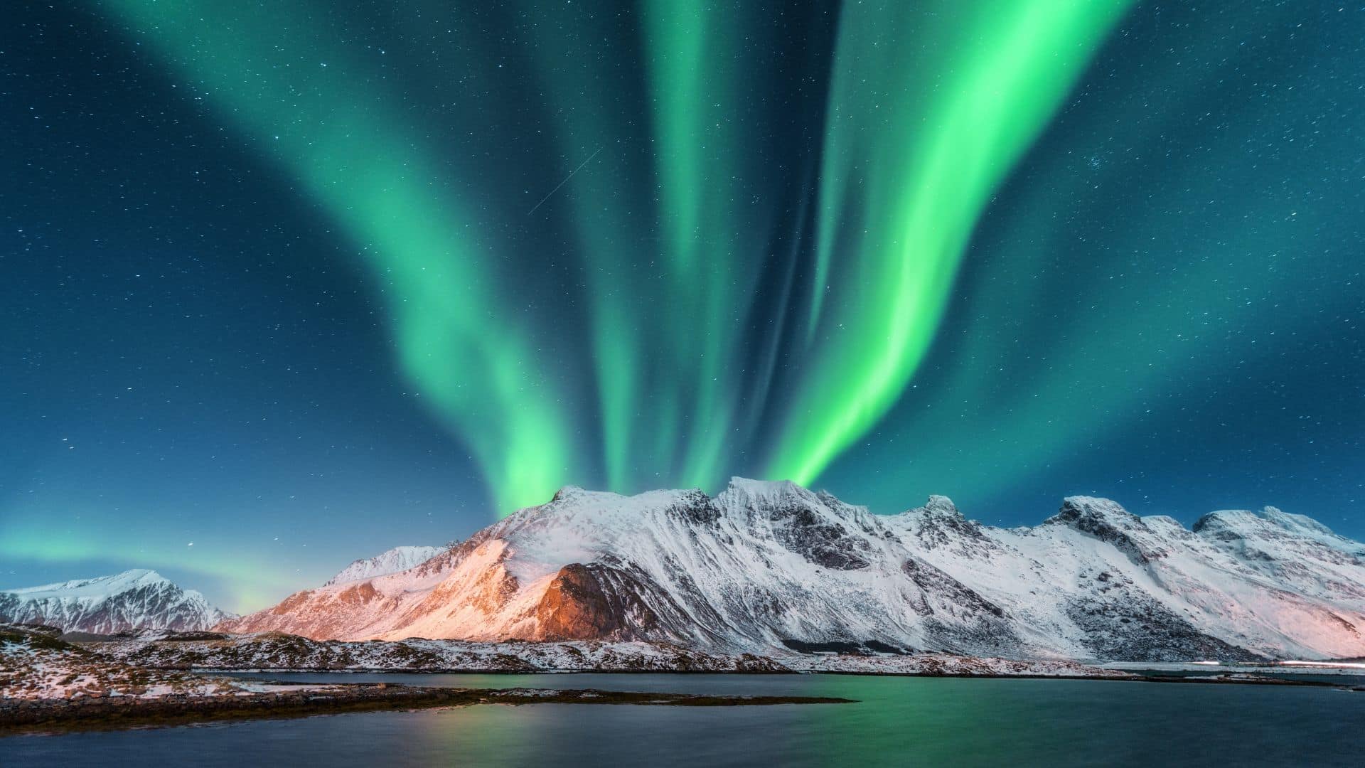 Aurores boréales vertes au-dessus de montagnes enneigées en Norvège
