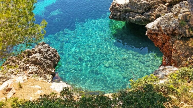 Crique rocheuse avec eau transparente et fond marin visible