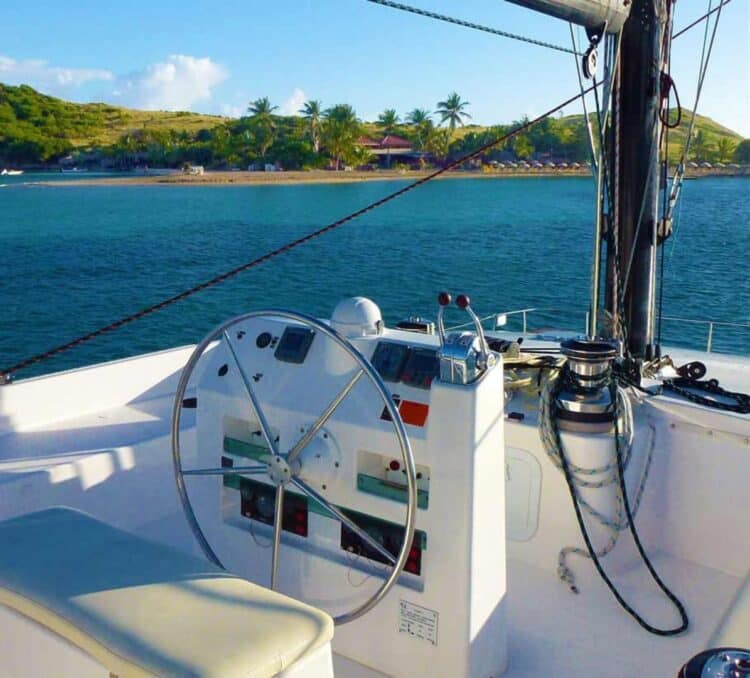Poste de pilotage de catamaran avec vue sur une île tropicale et eau calme