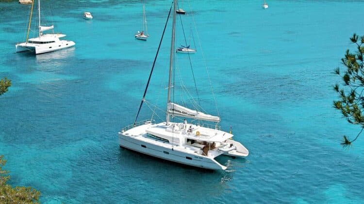 Catamaran ancré dans une eau turquoise vu de côté avec autres bateaux autour