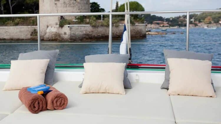 Espace détente sur le pont d’un catamaran avec coussins et vue sur le littoral