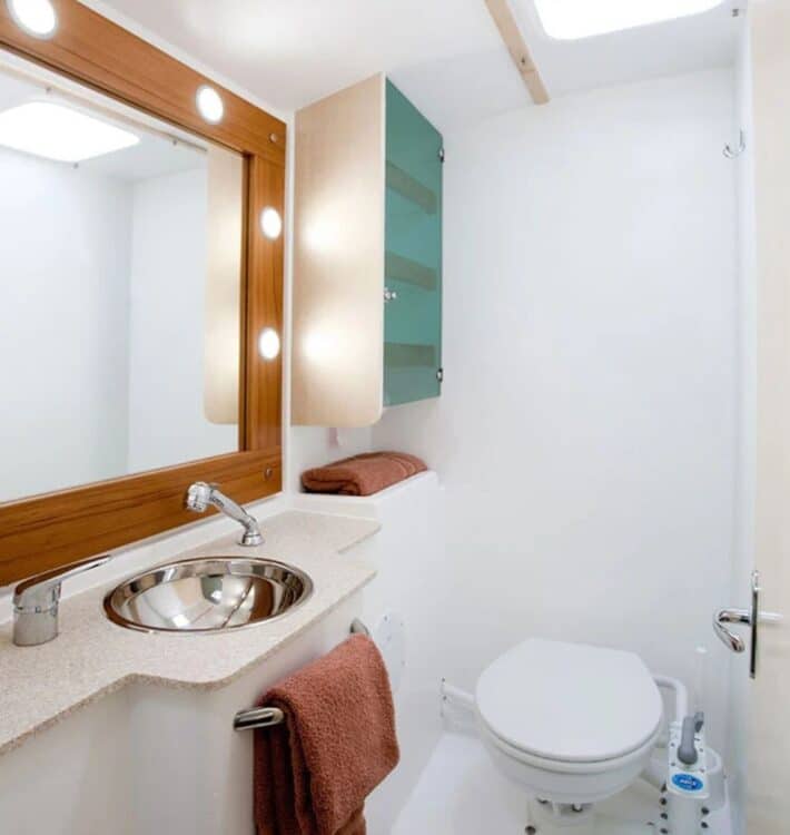 Salle de bain compacte et équipée à bord d’un catamaran avec lavabo miroir et toilettes