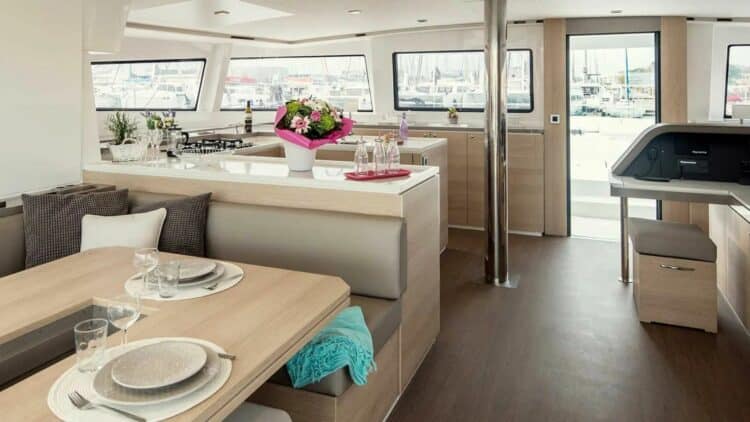 Grand salon lumineux de catamaran avec cuisine ouverte et vue sur le port