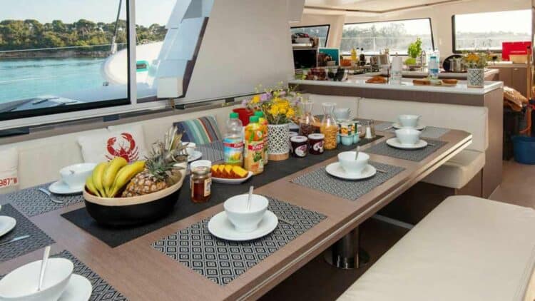 Table dressée pour le petit déjeuner sur un catamaran avec fruits et boissons