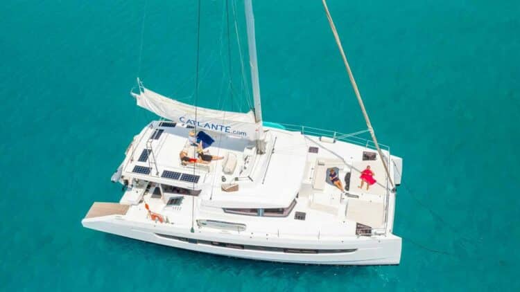 Vue aérienne d’un catamaran avec passagers se relaxant sur le pont dans une eau turquoise