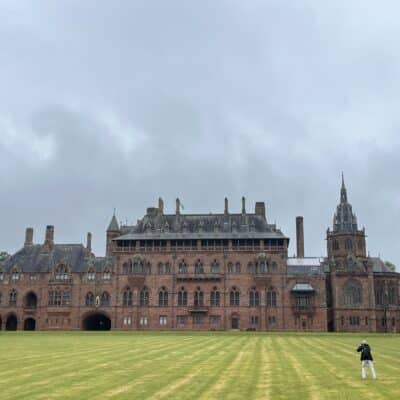 Château historique en Écosse entouré d’un vaste parc verdoyant sous un ciel nuageux.