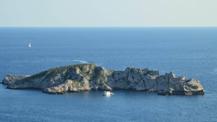 Île rocheuse du Frioul entourée par la mer Méditerranée avec un bateau à proximité