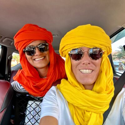 Deux voyageuses portant des chèches traditionnels colorés lors d’un circuit dans le sud du Maroc.