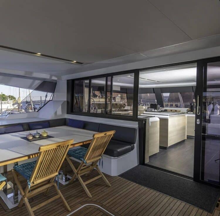 Terrasse arrière d’un catamaran avec table à manger et accès à l’intérieur