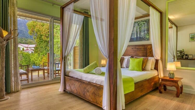 Chambre élégante de La Villa Soalic avec lit à baldaquin et décoration tropicale