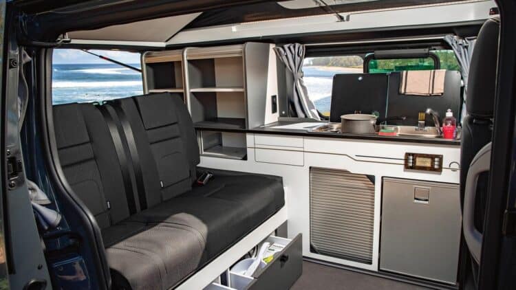 Intérieur d’un van aménagé avec banquette et espace cuisine équipé