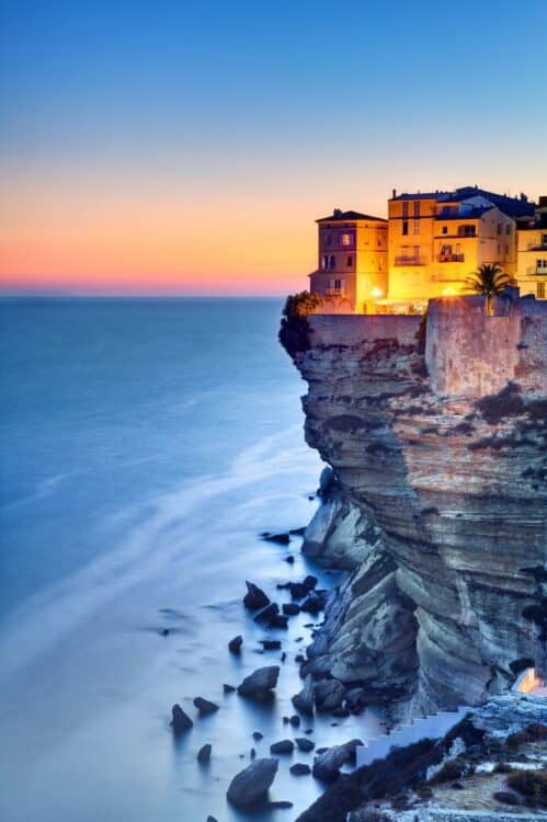 Maisons de Bonifacio perchées sur les falaises calcaires au coucher du soleil.