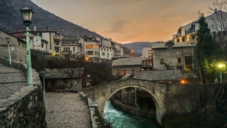 Pont en pierre et maisons historiques du centre de Mostar au coucher du soleil.